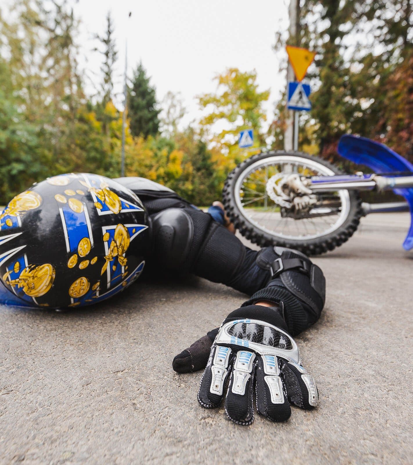 A motorcyclist prone on the street next to their bike after a motorcycle accident.