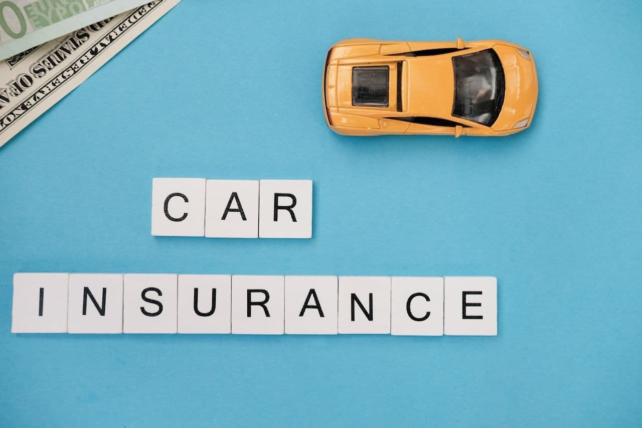 A toy car and letter tiles that spell out "car insurance." Ohio auto insurance requirements can be broken down simply.