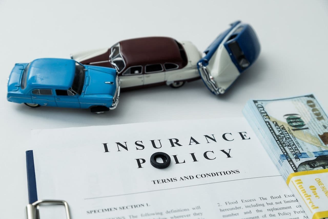 A paper insurance policy surrounded by cash and toy cars, symbolizing Oregon's car insurance requirements.